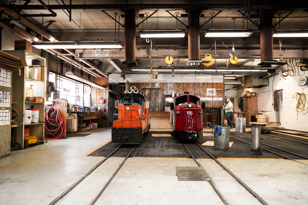 Two diesel locomotives sit inside a shop.