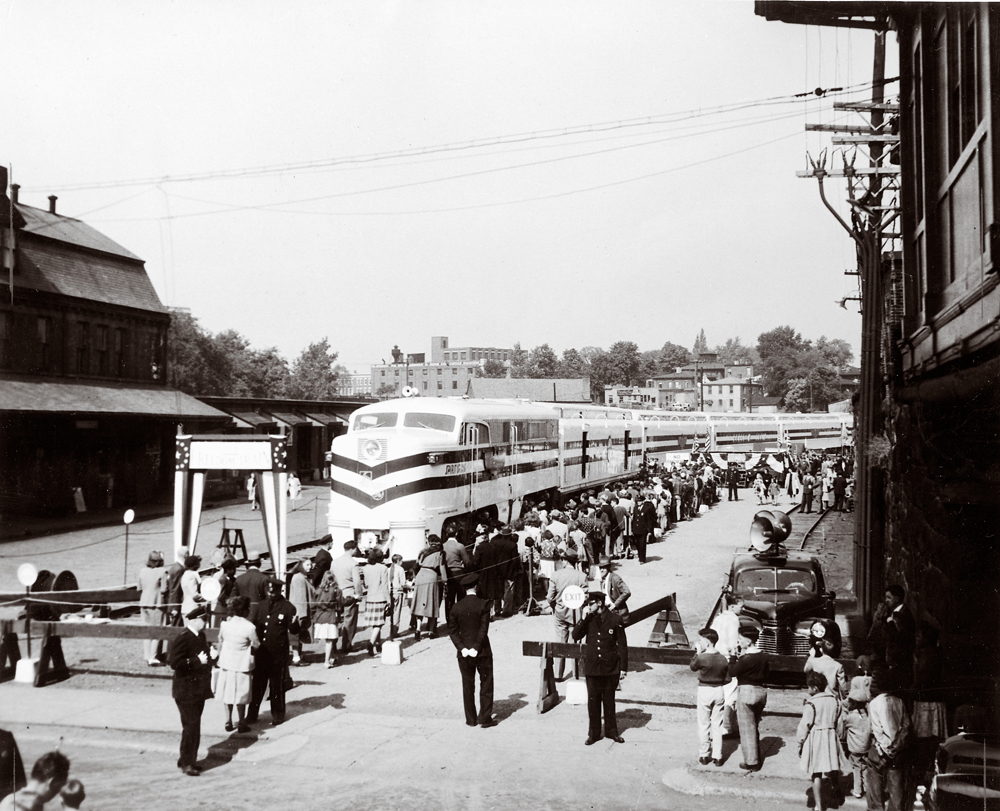 black-and-white image of train with crowds of people around it