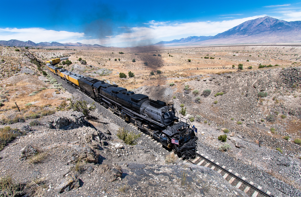 Steam locomotive and short train in desert passing below camera location. Elrond Lawrence photo