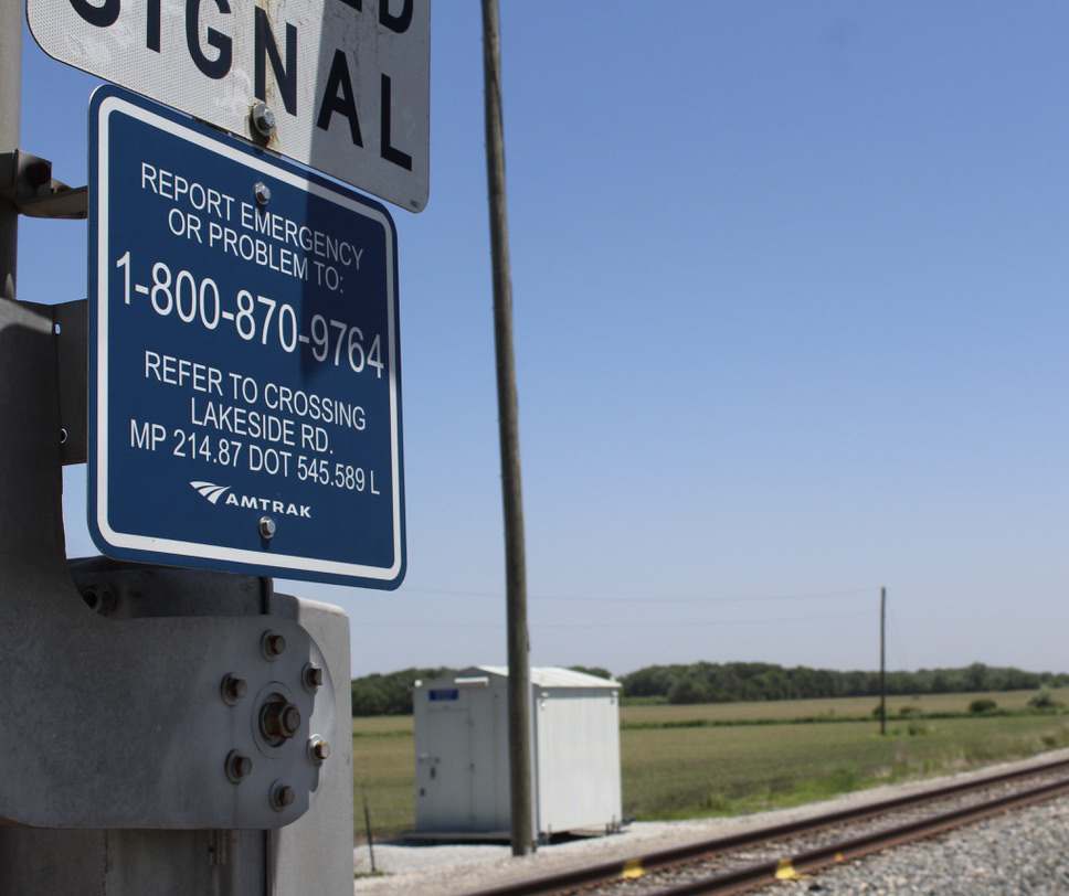 Blue emergency notification sign with grade crossing in background