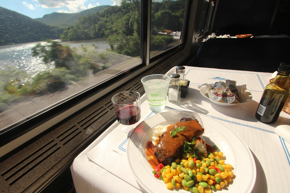 Food on table in dining car with view of river outside window
