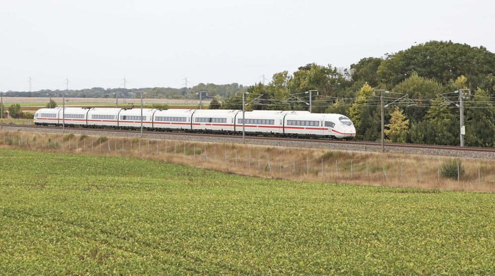 White high speed train with field in foreground