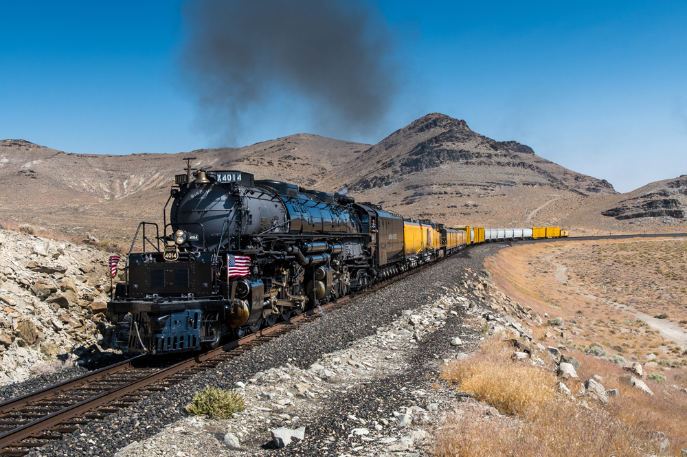 Steam locomotive and train round curve in desert landscape