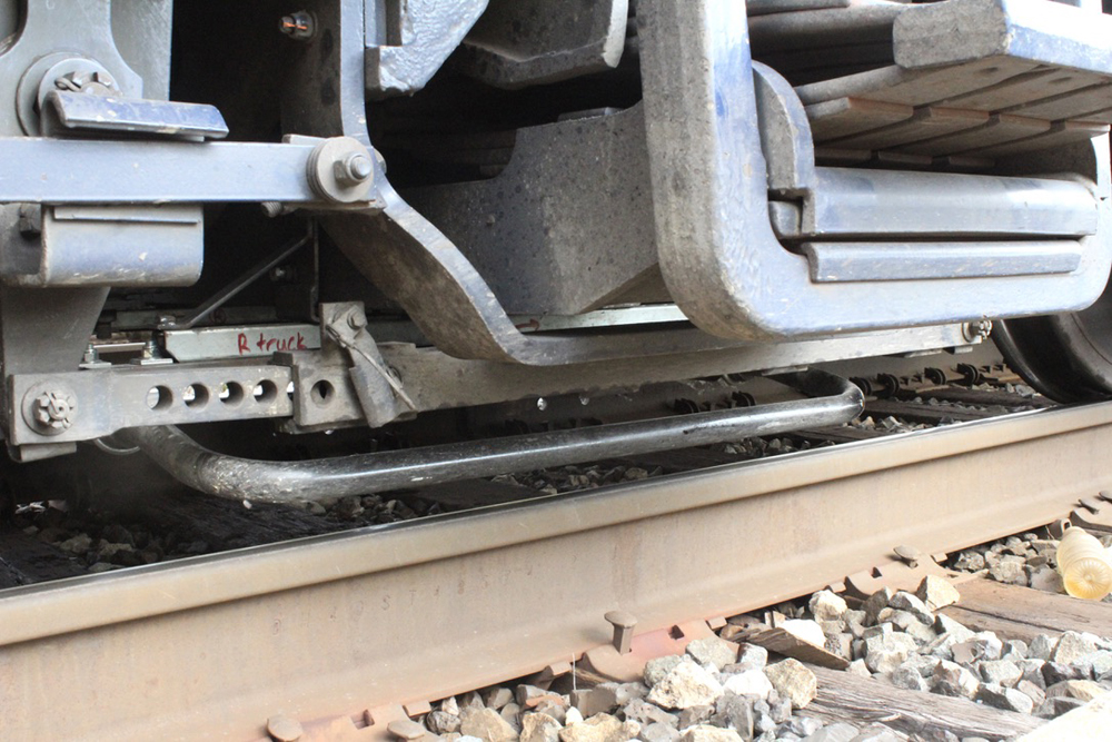 Close-up of locomotive truck showing bar-like object, the shunt-enhancing antenna, near top of rail.
