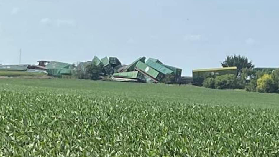 Stack of derailed containers and intermodal cars in field