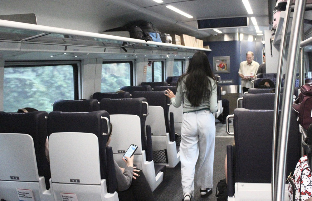 View looking from rear of coach with two people walking in aisle.