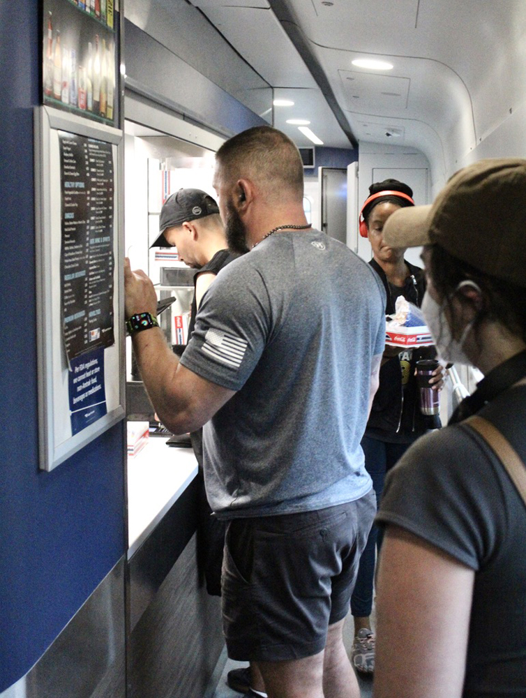 Several people standing in tight quarters in hallway of cafe car