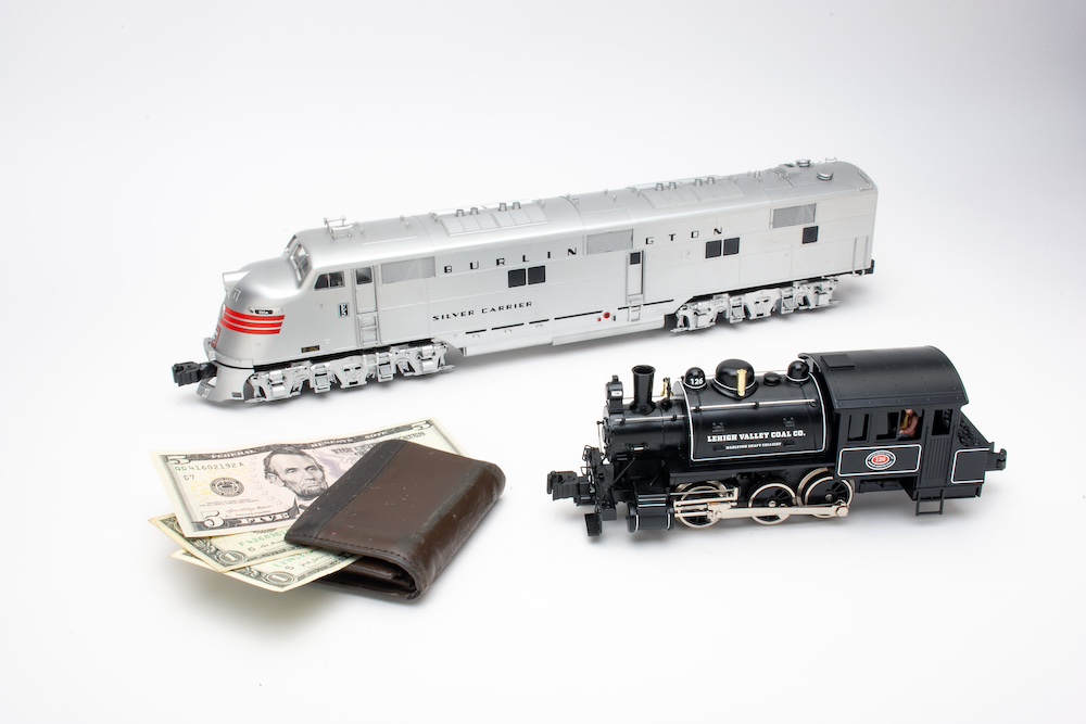 Model trains next to a wallet full of dollar bills.