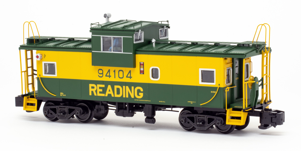 Color photo of green-and-yellow S gauge caboose on white background.