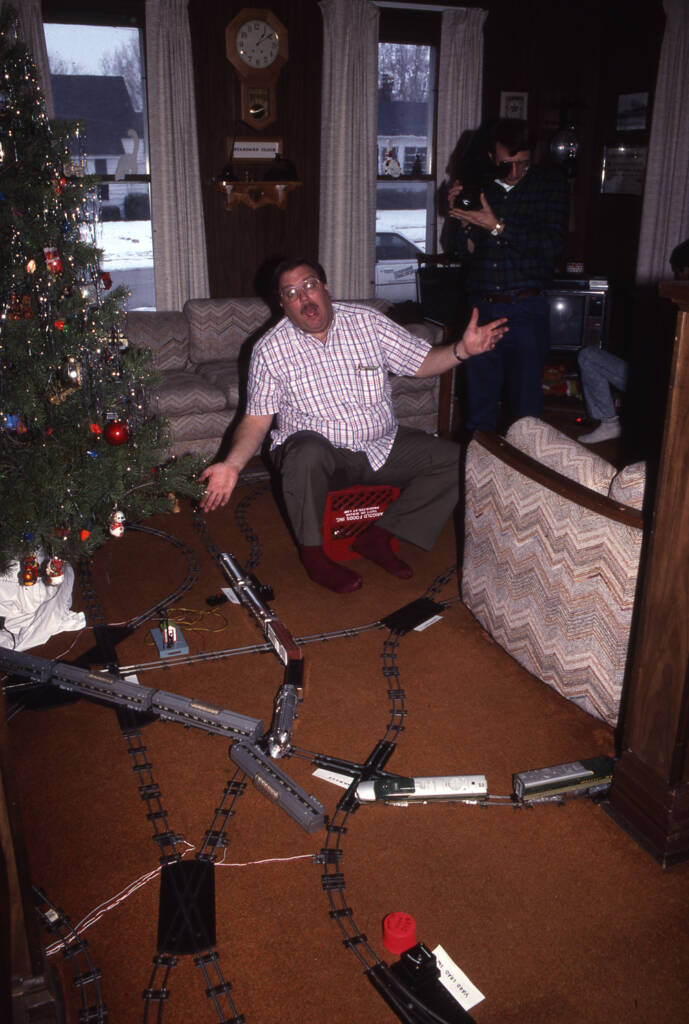 man with hands wide open near christmas tree