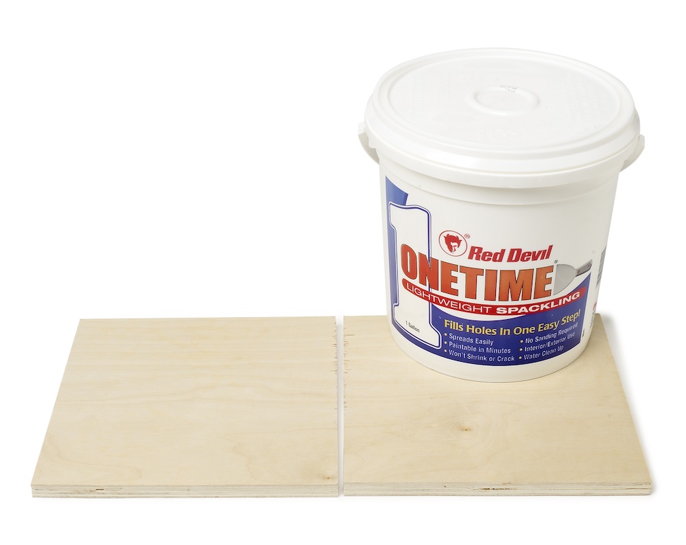 container of spackle and two pieces of plywood 