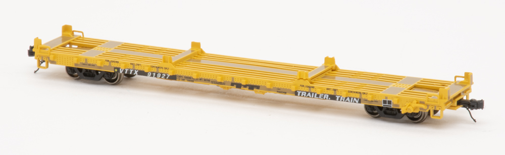 Color photo of yellow N scale flatcar on white background.