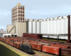 Photo of model railroad with grain elevator, switcher, and boxcars.