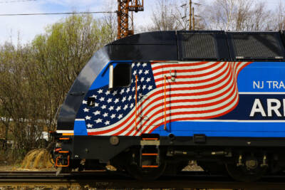 Front of blue electric passenger locomotive with U.S. flag graphic.