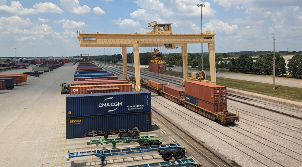 A freight crane is posed above multiple freight shipping containers in various colors