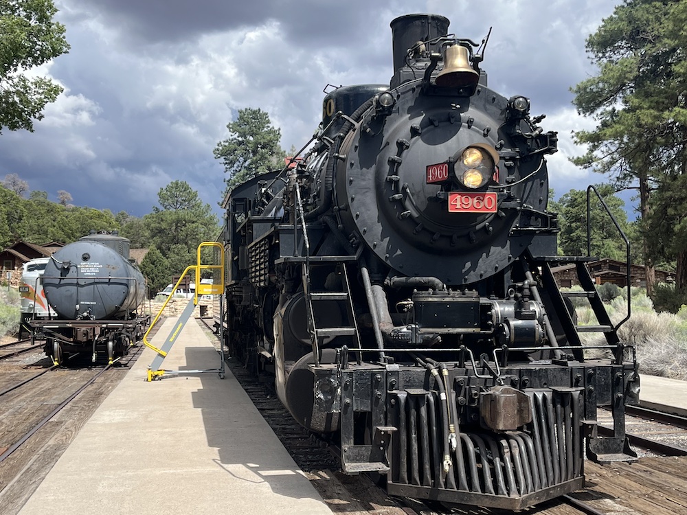 Steam locomotive sits next to tank car.