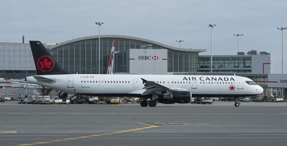 White airplane with blue tail with terminal building in background.