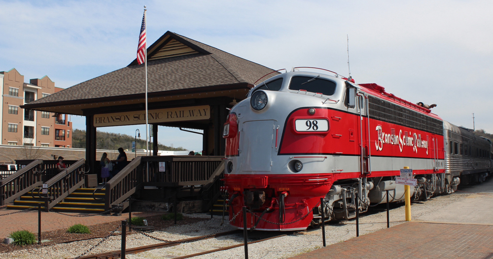 Red and grey F unit on passenger train in front of station