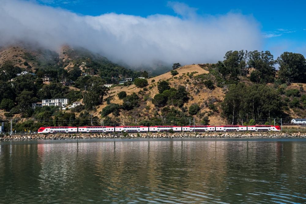 White and red electric train seen over the water