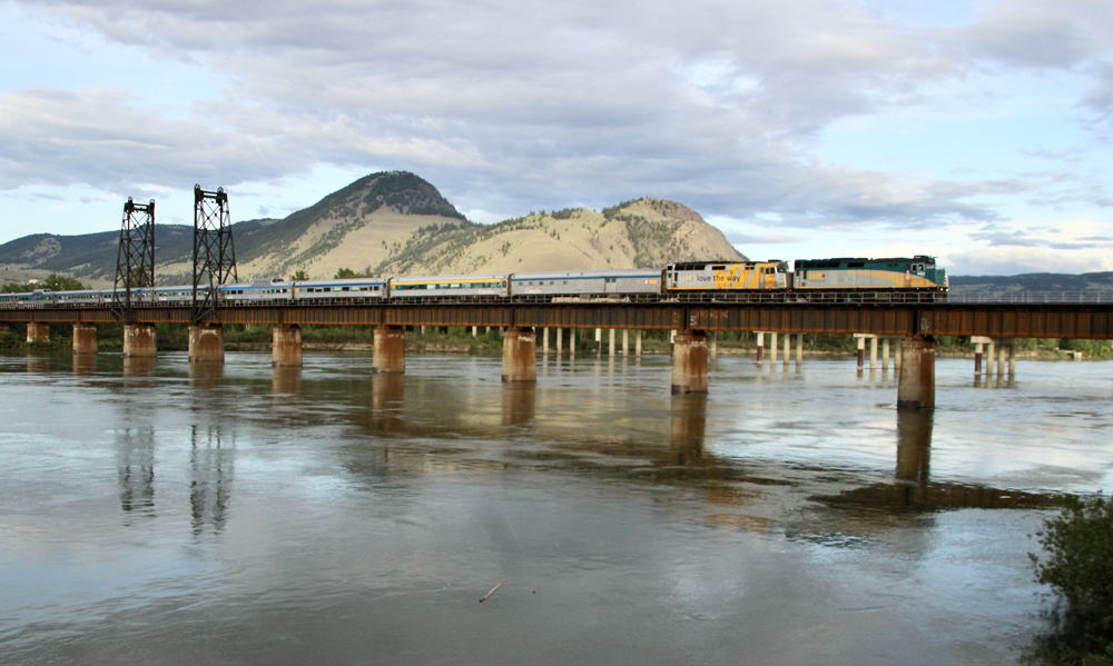 Passenger train crossing river bridge