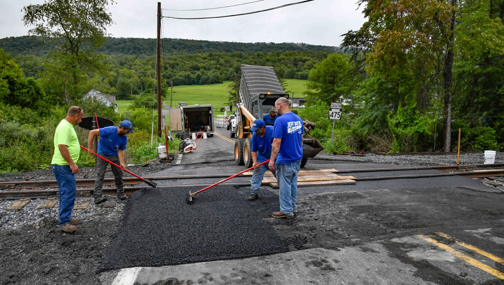 Men applying pavement at railroad grade crossing