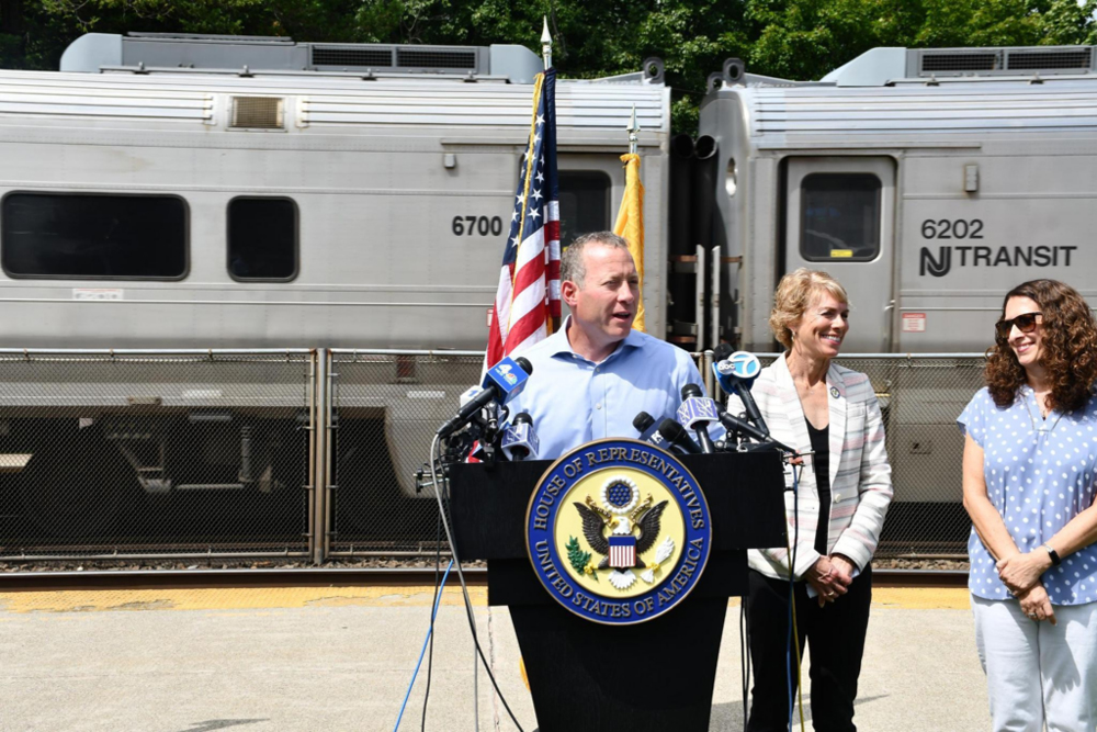 Man at podium with commuter train in background