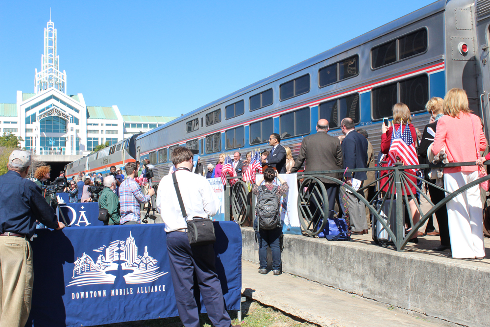 Crowd around passenger train with convention center building in background