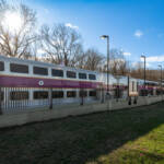 Silver bilevel coaches with purple coaches at station