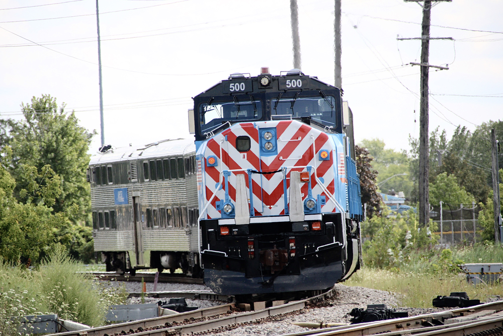 Blue locomotive with red and white stripes at the front pushes the train