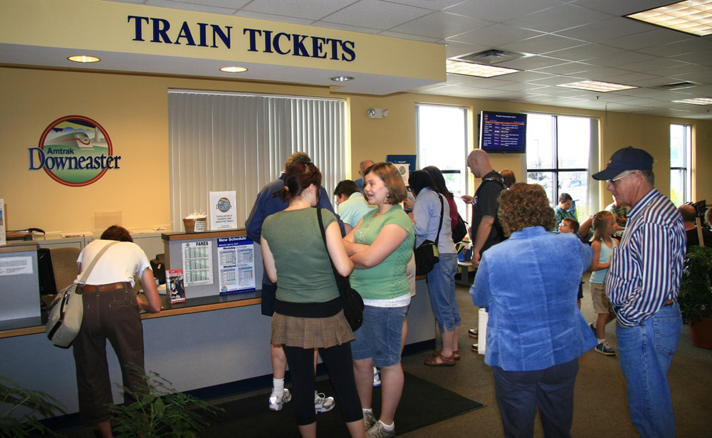 People gathered in front of the counter with a sign reading "Train tickets"