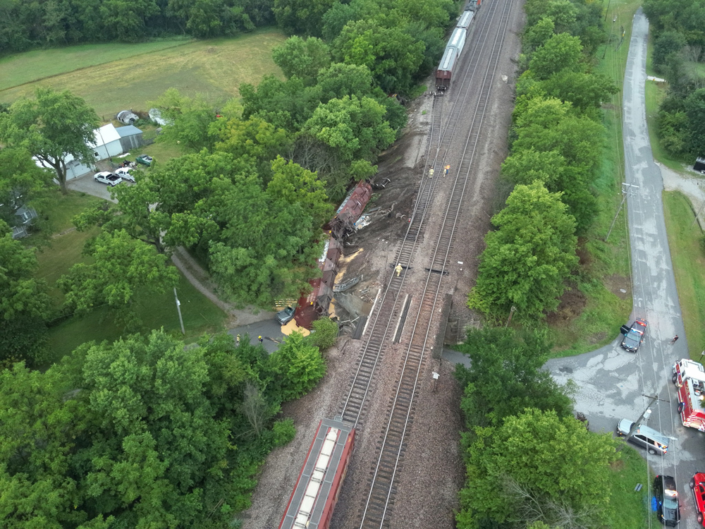 Aerial view of derailed cars that have fallen down embankment along tracks