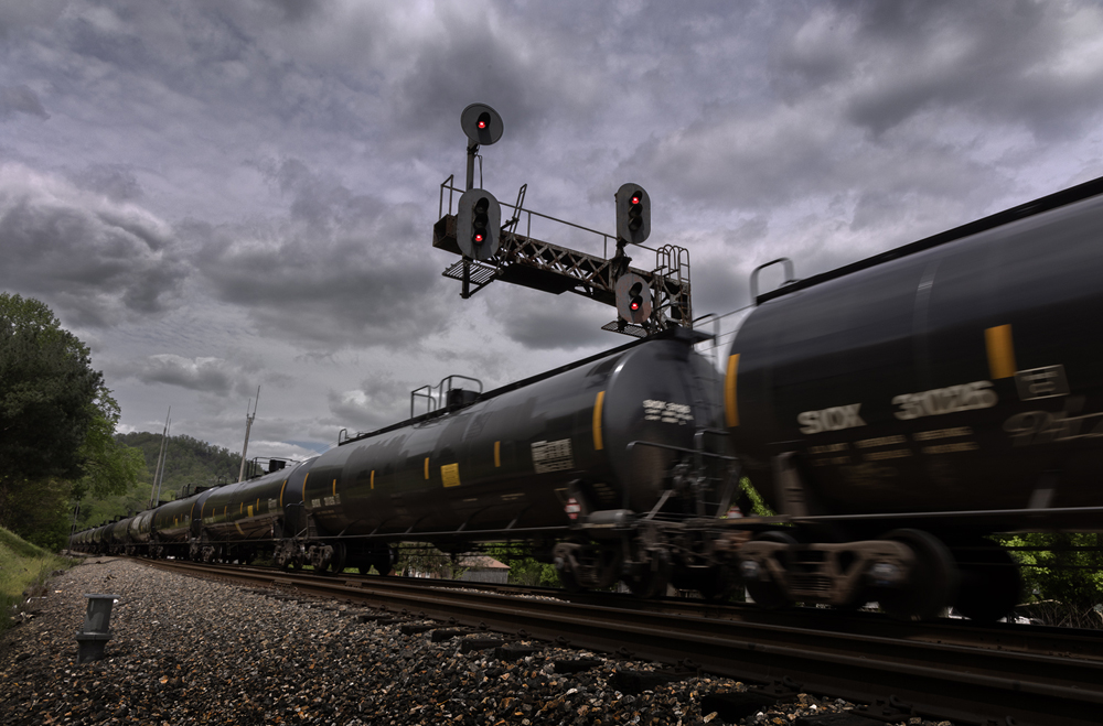 Tank cars pass under signal on cloudy day