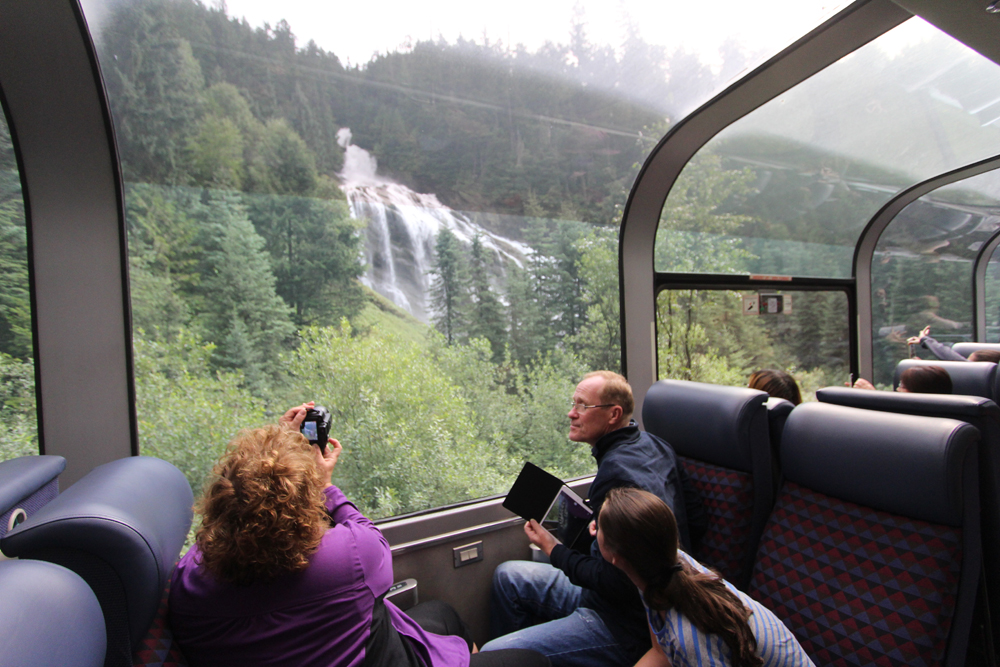 Passengers look at waterfall from seats in dome car