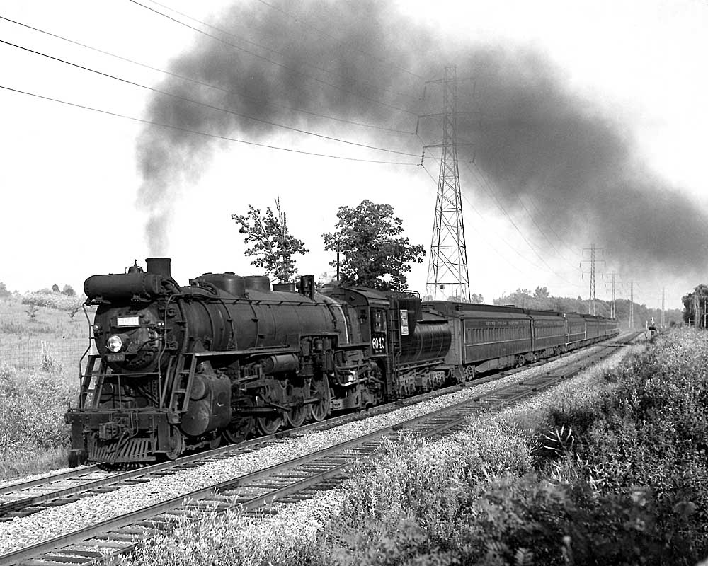 Steam locomotive with Detroit commuter trains under high-tension power lines