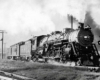 Steaming and smoking steam locomotive with passenger train on curve