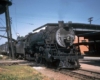 Steam locomotive with passenger train by water tank on crossing railroad track