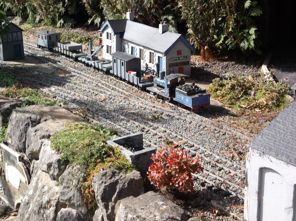 model train rests near station on garden railway; adventure in imagination