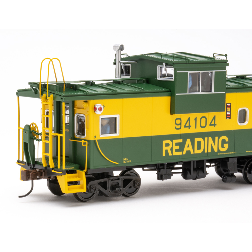 Color photo of green and yellow caboose on white background.