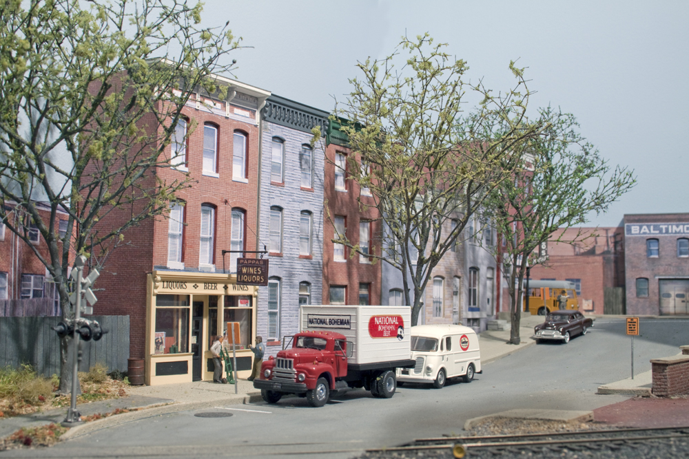 Color photo of structures, vehicles, figures, and trees on HO scale layout.