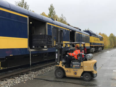 Folklift loading a baggage car.