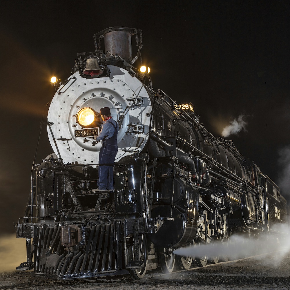 Steam locomotive at night with crew member up on the front with Santa Fe No. 2926 to make another visit to Albuquerque’s Rail Yard for Railroad Days