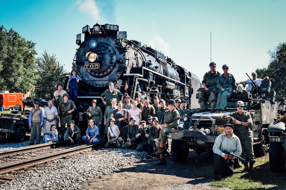 Steam locomotive with World War II reenactors and vehicles