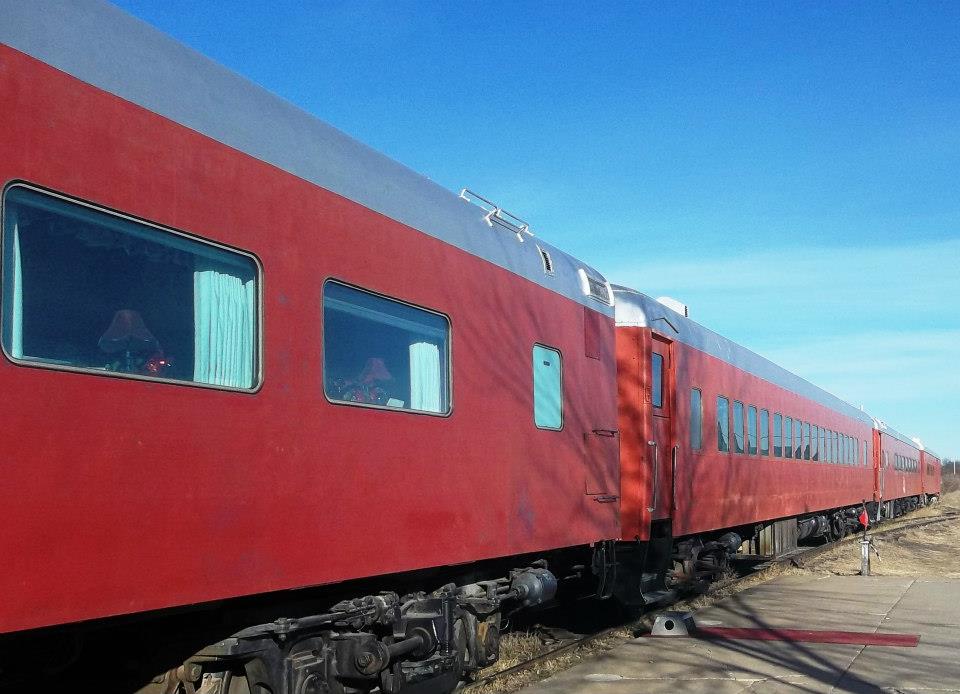 Red-colored passenger cars outside a clear day after Kansas Belle dinner train cars find temporary home at Abilene & Smoky Valley