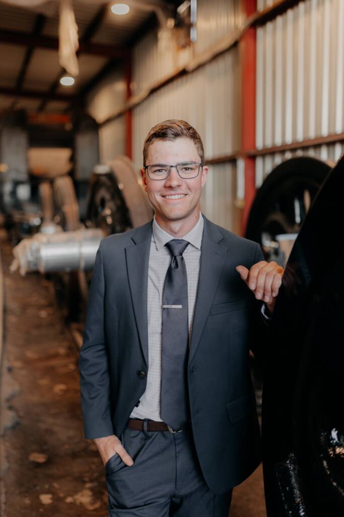 Young individual standing next to a disassembled driving wheel of a steam locomotive