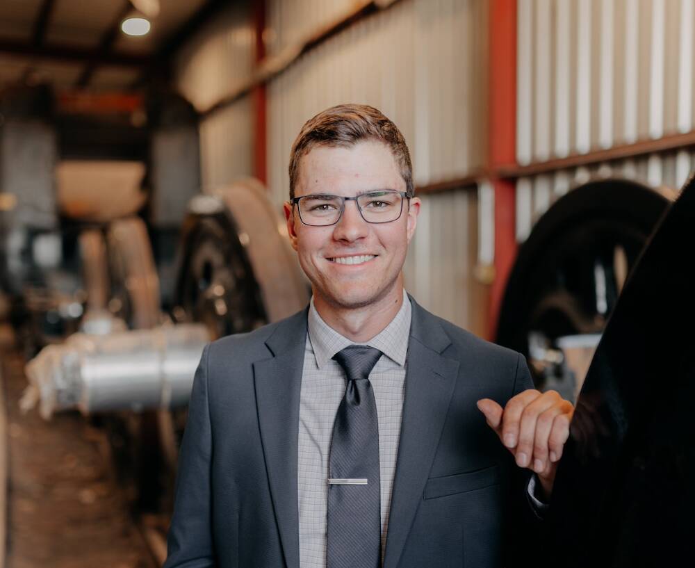 Young individual standing next to a disassembled driving wheel of a steam locomotive