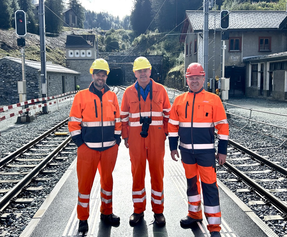 Three people in orange safety clothing with tunnel in background