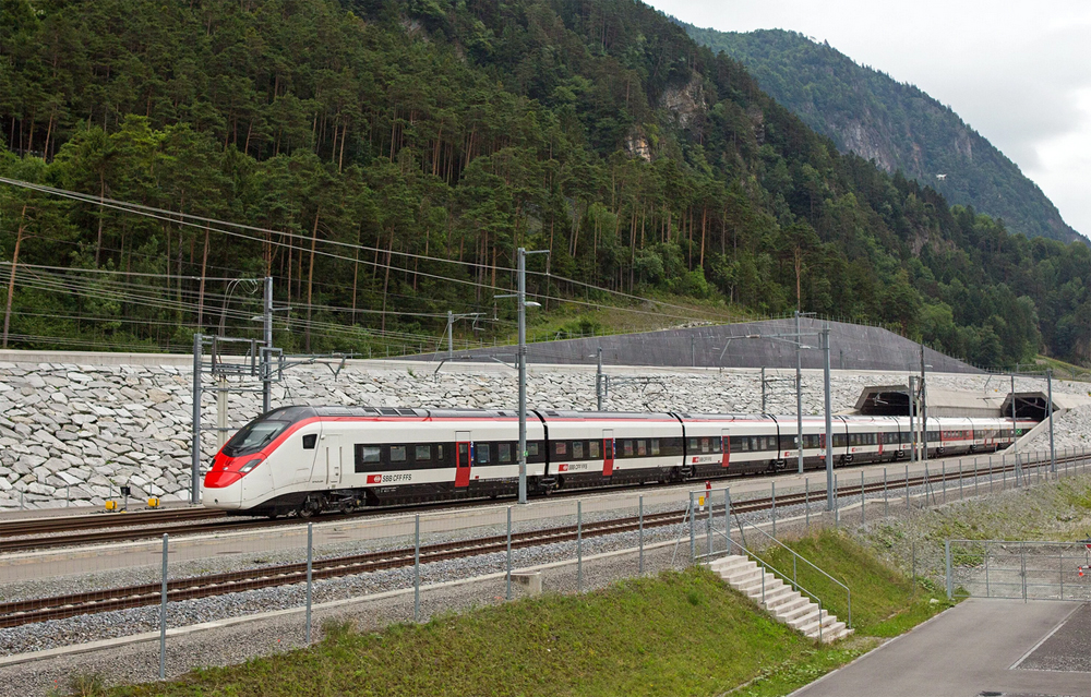 Red and white passenger train at tunnel portal