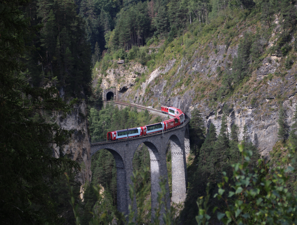 Telephoto view of train on curved stone bridge