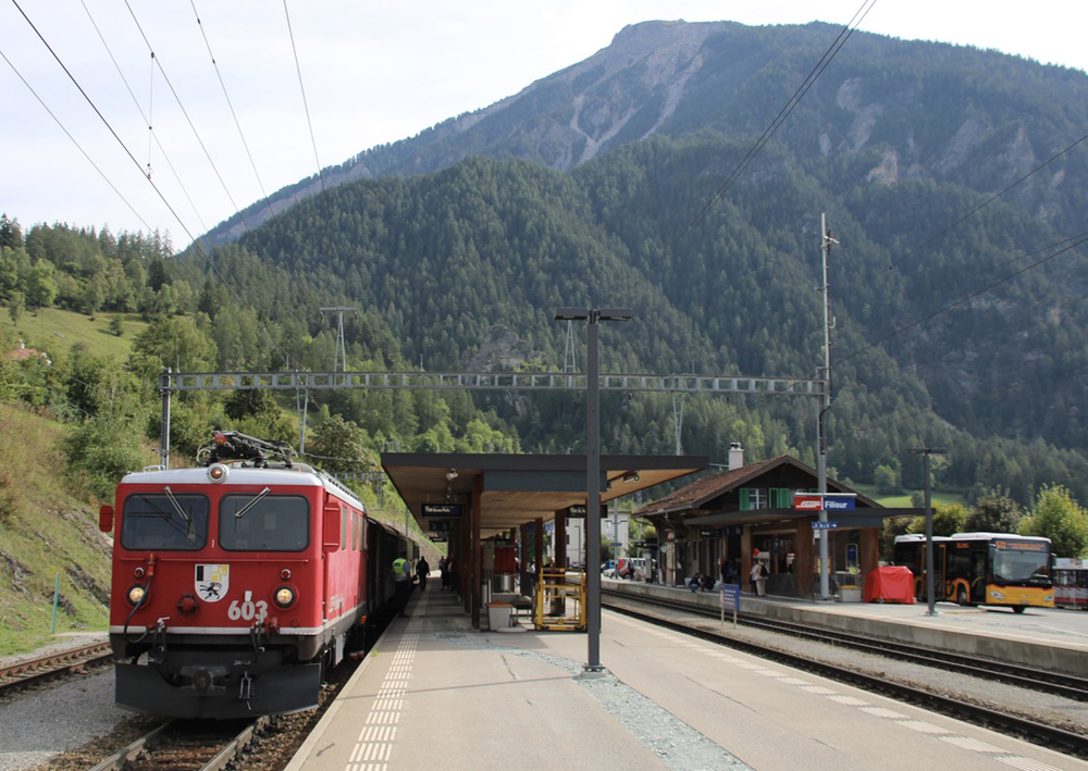 Red locomotive and vintage railcars at station