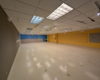 A now-empty room which formerly held a sprawling model railroad layout. The walls are yellow and blue. The floor and ceiling are white.